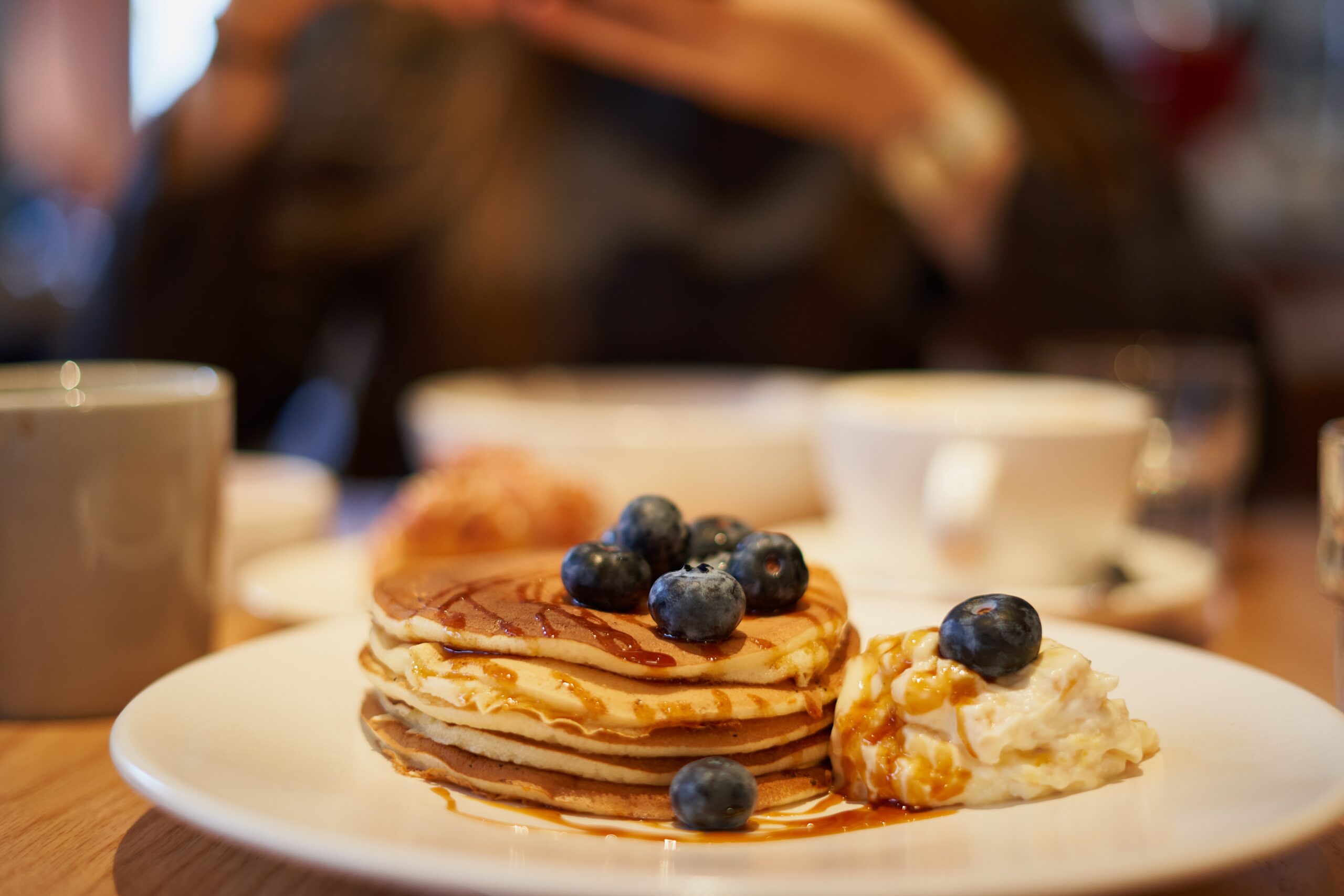 sweet pancakes with caramel syrup, blueberries and ice cream on plate in cafe